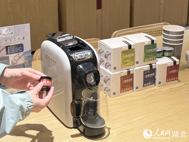 店员给游客展示一键出汤的胶囊泡茶机。人民网记者 周恬摄