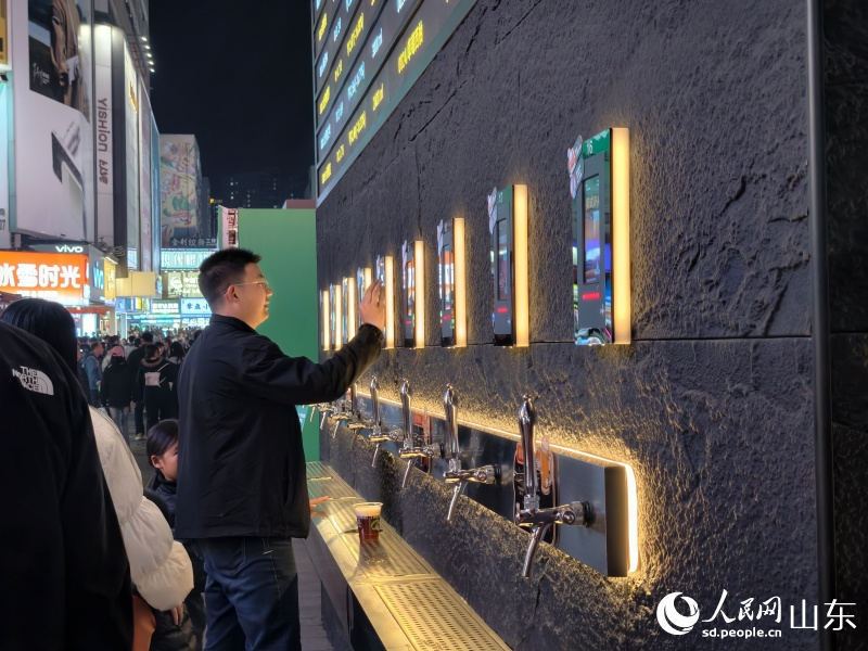 游客在“青岛啤酒交易所”前体验接啤酒。人民网记者 刘颖婕摄